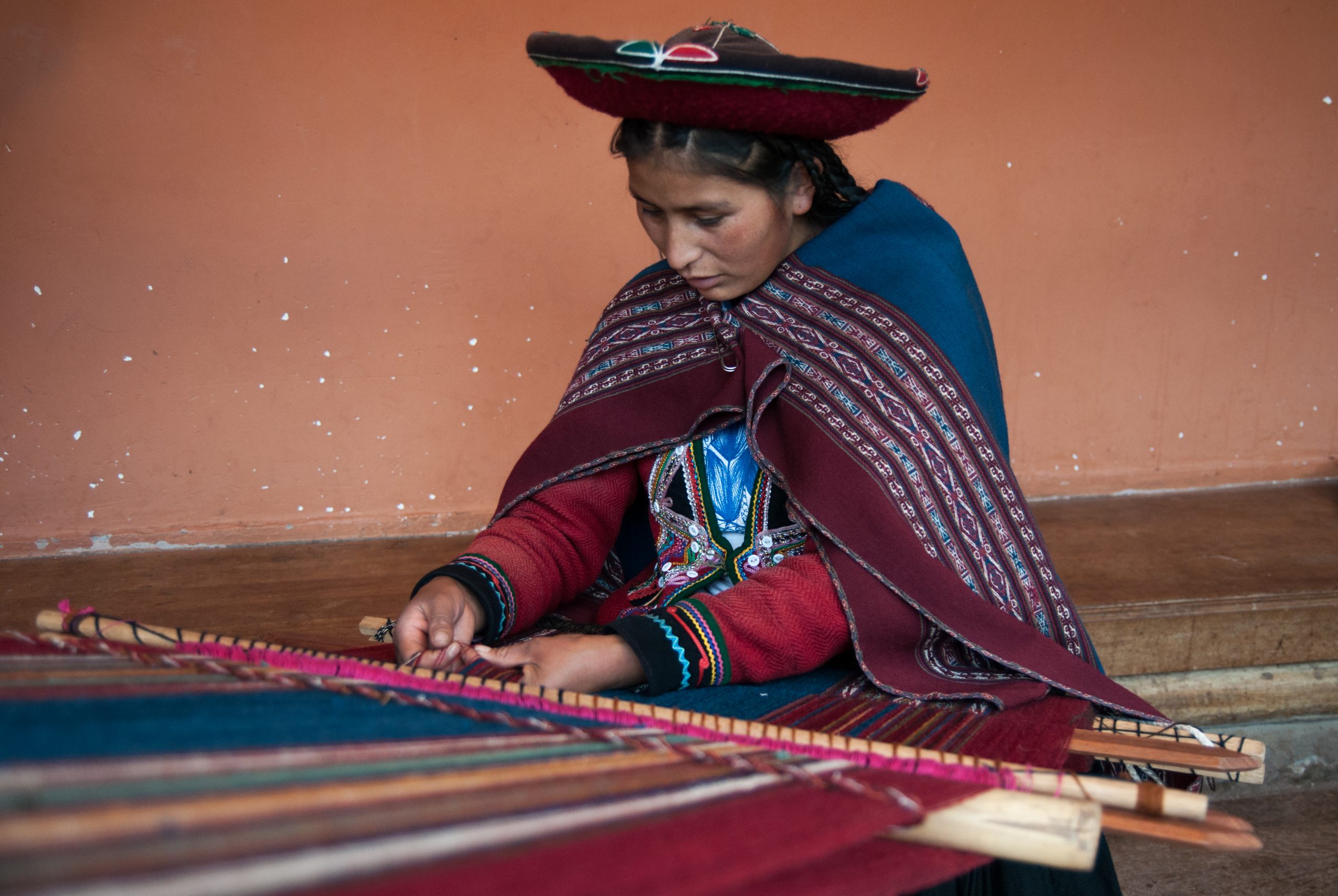 A woman at the Chinchero Weaving Collective works on a loom