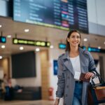 Happy,Female,Traveler,Walking,Towards,Departure,Gate,At,The,Airport.